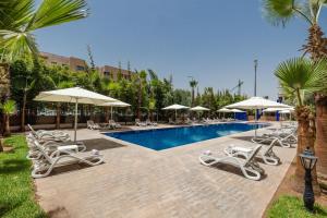 a swimming pool with lounge chairs and umbrellas at Wazo Hotel in Marrakesh