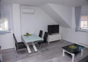 sala de estar blanca con mesa y TV en Apartmaji Anita, en Begunje pri Cerknici