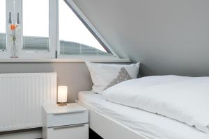 a white bedroom with a bed and a window at Appartement Lille Kamp 2 in Westerland