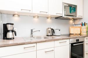 a kitchen with white cabinets and a sink at Appartement Lille Kamp 2 in Westerland