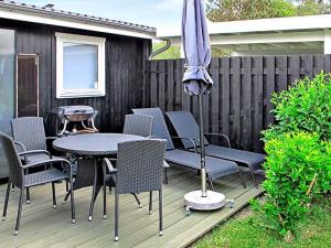 um pátio com uma mesa, cadeiras e um guarda-sol em 6 person holiday home in Dannemare em Dannemare