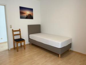 a bed and a chair in a room at Wohnung mit 2 Einzelzimmer gemeinsamer Küchen/Bad/Balkon-Nutzung in Espelkamp
