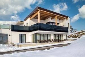 ein weißes Haus mit schwarzen Fenstern im Schnee in der Unterkunft Gabriela Appartements in Serfaus