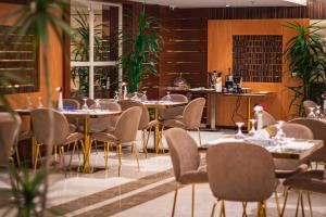 a restaurant with tables and chairs and plants at Towers Hotel in Buraydah