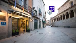 a city street with buildings and a clock on the wall at Real Segovia by Recordis Hotels in Segovia