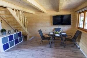 a room with a table and chairs and a television at Dadaj Summer Camp - całoroczne domki Rukławki in Biskupiec
