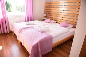 1 dormitorio con 1 cama grande con sábanas blancas y almohadas rosas en Dom Gościnny Pod Akacjami, en Zbąszyń