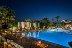 a pool at night with tables and chairs at Avithos Resort Hotel in Svoronata