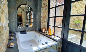 una gran bañera blanca en una habitación con ventanas en Apartamentos El Rincón de Usana Zona Zero, en Aínsa