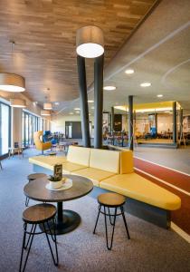 eine Lobby mit einem gelben Sofa und 2 Tischen in der Unterkunft JUFA Hotel Erlaufsee in Mariazell