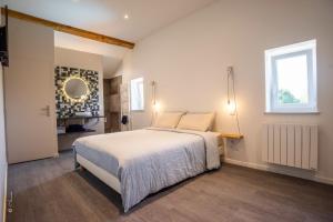 ein Schlafzimmer mit einem großen weißen Bett und einem Fenster in der Unterkunft LA DOLOREANNE in Saint-Didier-sur-Chalaronne