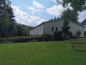 a large white building with a bench in a yard at Pension Harzbaude Susanne - Garni in Rübeland