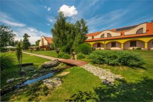 a house with a garden and a stream in front of it at Wellness hotel Spark in Malacky