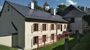 um edifício branco com um telhado preto e janelas vermelhas em Měšťanský dům - kulturní památka Mlýnská 119 em Jindrichuv Hradec