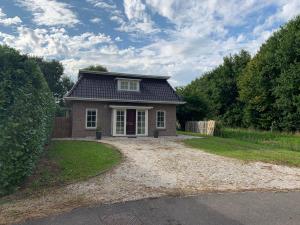 a small house with a black roof on a gravel driveway at Vakantiehuis Villa Zeewolde in Zeewolde