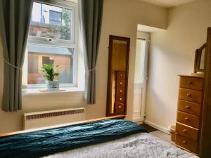a bedroom with a bed and a window and a dresser at Chapel St Apartments in Caernarfon