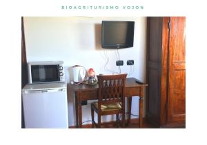 ポンティ・スル・ミンチョにあるBio Agriturismo Vojonのキッチン(テーブル、テレビ、デスク、椅子付)