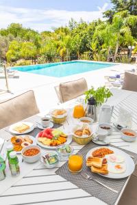 - une table avec de la nourriture pour le petit-déjeuner à côté de la piscine dans l'établissement Fazenda Viegas, à Lagos