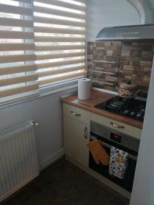 uma cozinha com fogão e uma janela com persianas em Apartament Atena em Petroşani