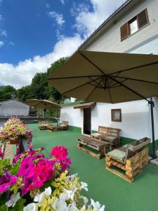 a patio with a large umbrella and benches and flowers at Claudia B&B in Pescasseroli