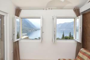 a room with two windows with a view of a lake at J & P Apartments Orahovac in Kotor