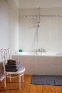 ein Badezimmer mit einer Badewanne und einem Stuhl mit Handtüchern in der Unterkunft Kasteel Duras in Sint-Truiden