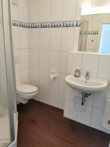 a white bathroom with a toilet and a sink at Ostseeapartment in Graal-Müritz