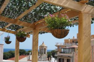 a wooden pergola with two potted plants hanging from it at Hotel Boutique OMA in Sant Feliu de Guíxols