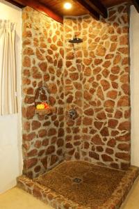a stone shower in a bathroom with a stone wall at Colibri Hotel in Baie Sainte Anne