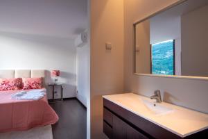 a bathroom with a bed and a sink and a mirror at Feel Discovery Douro Cherry in Resende