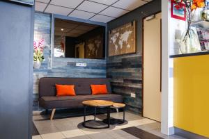 a couch in a lobby with orange pillows and a stool at Hotel Jesse in Amsterdam