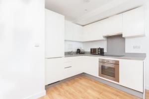 a kitchen with white cabinets and stainless steel appliances at Skyvillion - COZY APARTMENTS in Enfield Town With Free Parking & Wifi in Enfield
