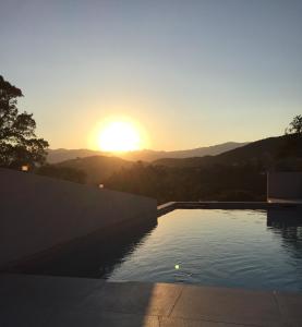 una piscina con vistas a la puesta de sol. en Villa Mamago, en Cirendinu
