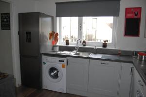 a kitchen with a refrigerator and a washing machine at Creag Mhor Self Catering Holiday Apartment in Aberfoyle