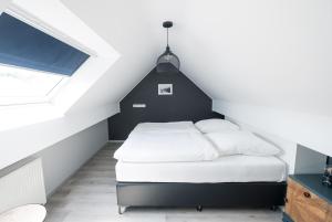 a bedroom with a black and white bed in a attic at Hotel-Restaurant Beim Schlass in Wiltz