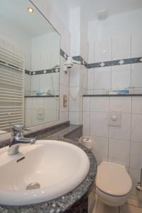 a bathroom with a sink and a toilet and a mirror at Inselhotel Ihnken in Norderney