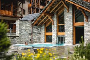 a swimming pool in front of a house at Alagna Mountain Resort & SPA in Alagna Valsesia