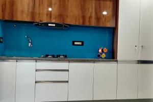 a kitchen with white cabinets and a blue wall at RESTEL STUDIO FLATS in Hyderabad