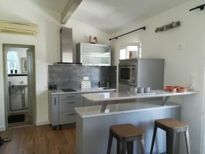 a kitchen with stainless steel appliances and stools at GITE AVEC SPA JACUZZI au cœur de Provence Côte d'Azur in Saint Antonin du Var