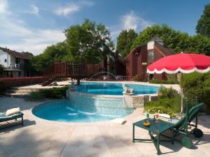 a swimming pool in a yard with a table and an umbrella at Hôtellerie Du Bas-Bréau in Barbizon
