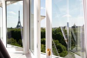 een open raam met uitzicht op de eiffeltoren bij Le Damantin Hôtel & Spa in Parijs