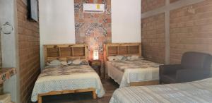 Habitación con 2 camas y una silla. en Hotel Villa de Urike en Urique