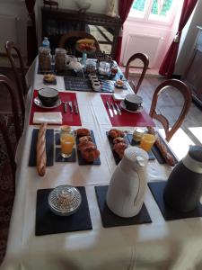 una mesa con alimentos para el desayuno y zumo de naranja en ella en LE MOULIN A VENT, en Bertric-Burée