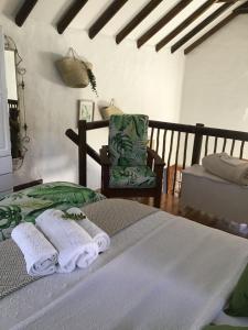 a bedroom with a bed and a chair with towels at The Greenery in Velddrif