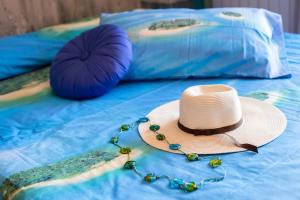 słomiany kapelusz i koraliki na łóżku z poduszkami w obiekcie B&B Il geco w mieście Sant'Agnello