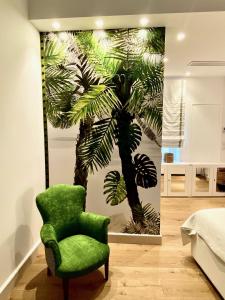 una silla verde en una habitación con una pintura de una palmera en B&B Al Vico en Trani