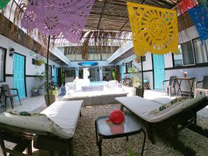 a patio with two beds and tables and purple umbrellas at Hotel Perico Azul & Surf Camp in Jacó