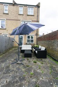 TownHouse4bedRoomHouse في West Dulwich: وجود مظلة زرقاء كبيرة في الفناء مع الأرائك