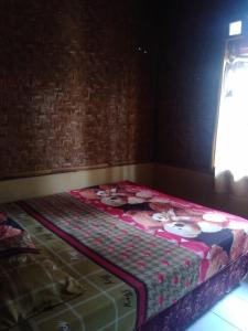 a large bed in a room with a wall at Pondok Pusaka Alam 2 Pangandaran in Pangandaran