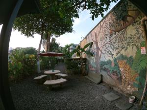 a wall with a table and benches and a mural at Hotel Perico Azul & Surf Camp in Jacó